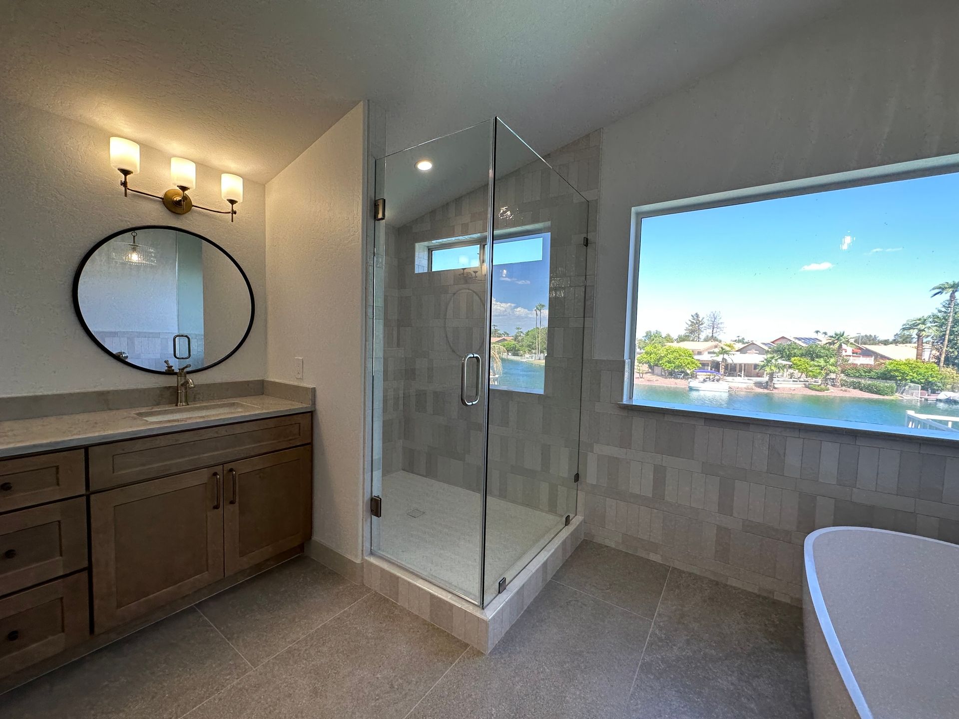 A bathroom with a walk in shower, sink, mirror, and tub.