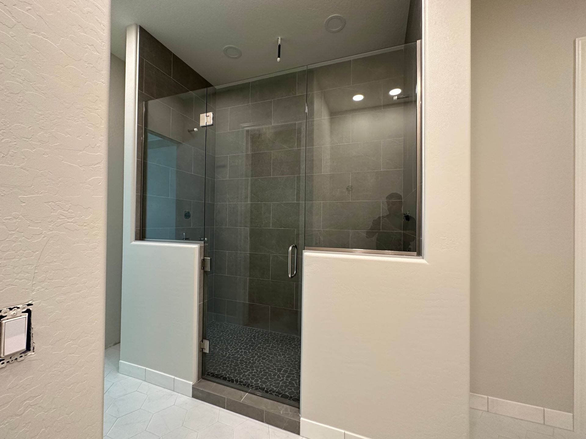 A bathroom with a walk in shower with a glass door.