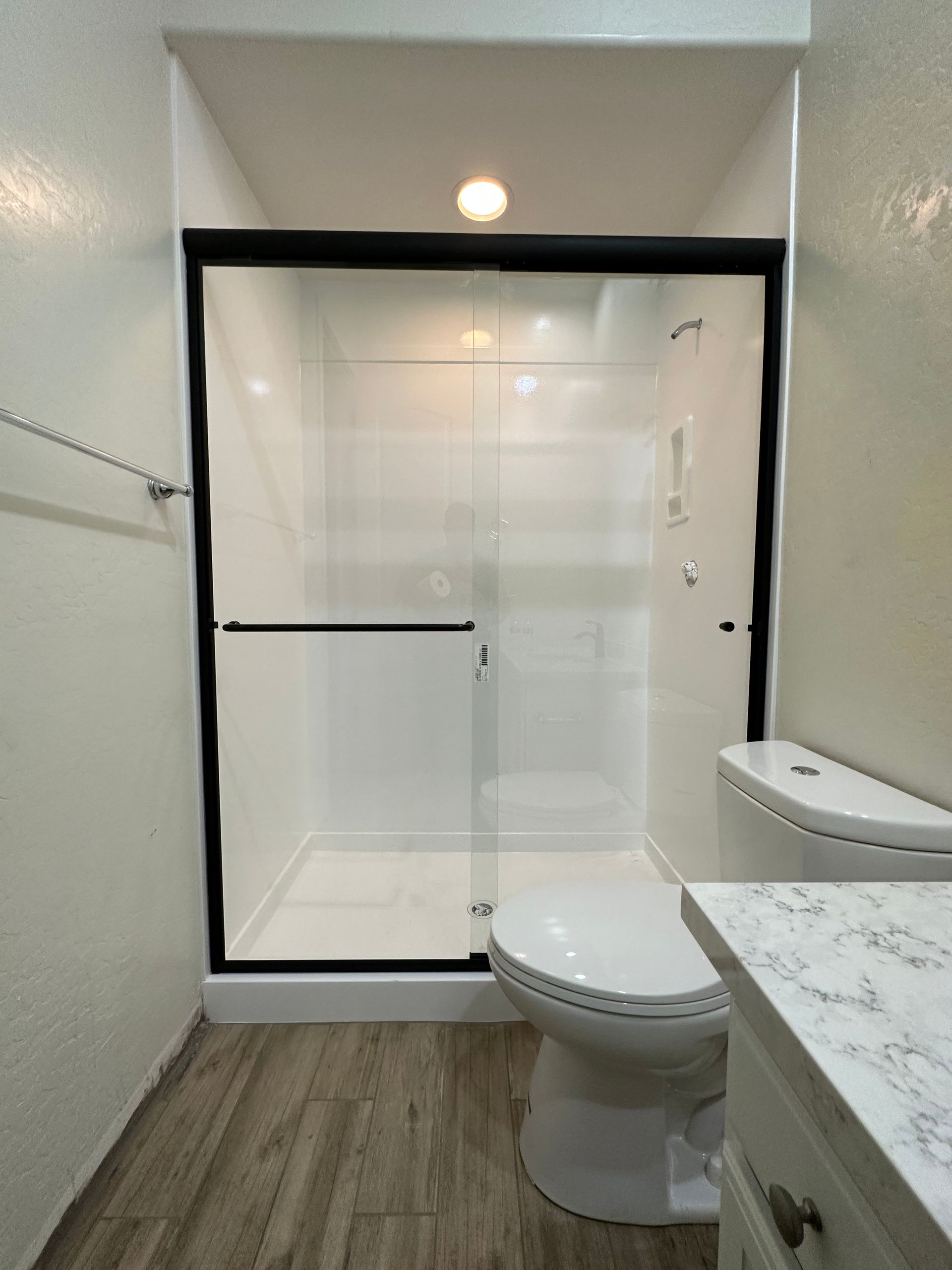 A bathroom with a toilet and shower with a sliding glass door.