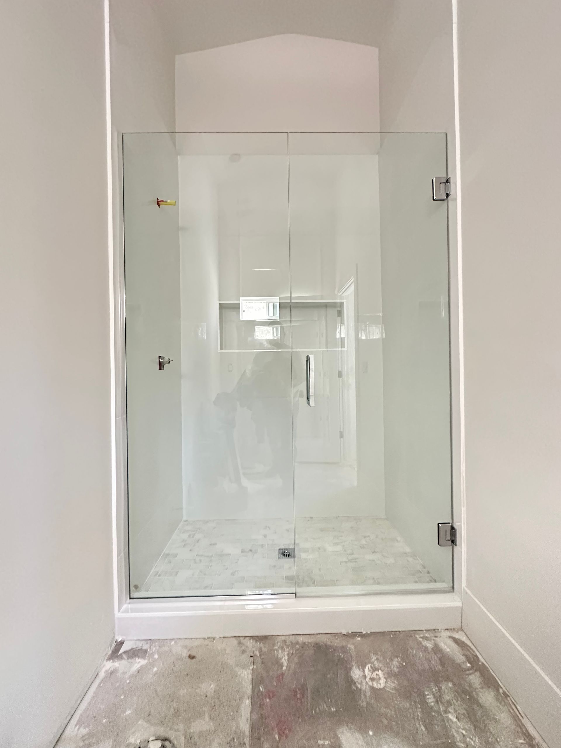 A bathroom with a walk in shower with a glass door.