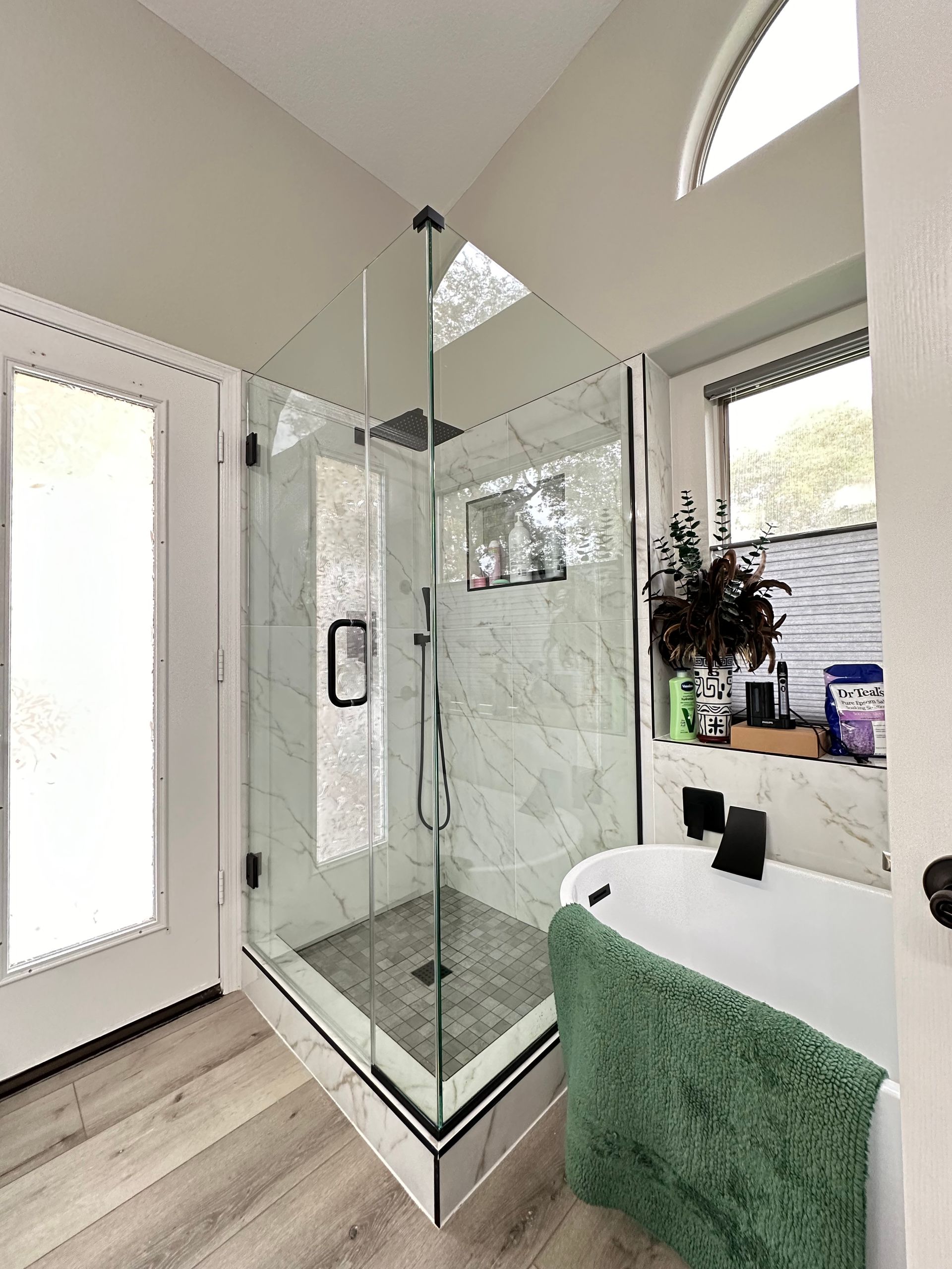 A bathroom with a tub, shower, and window.