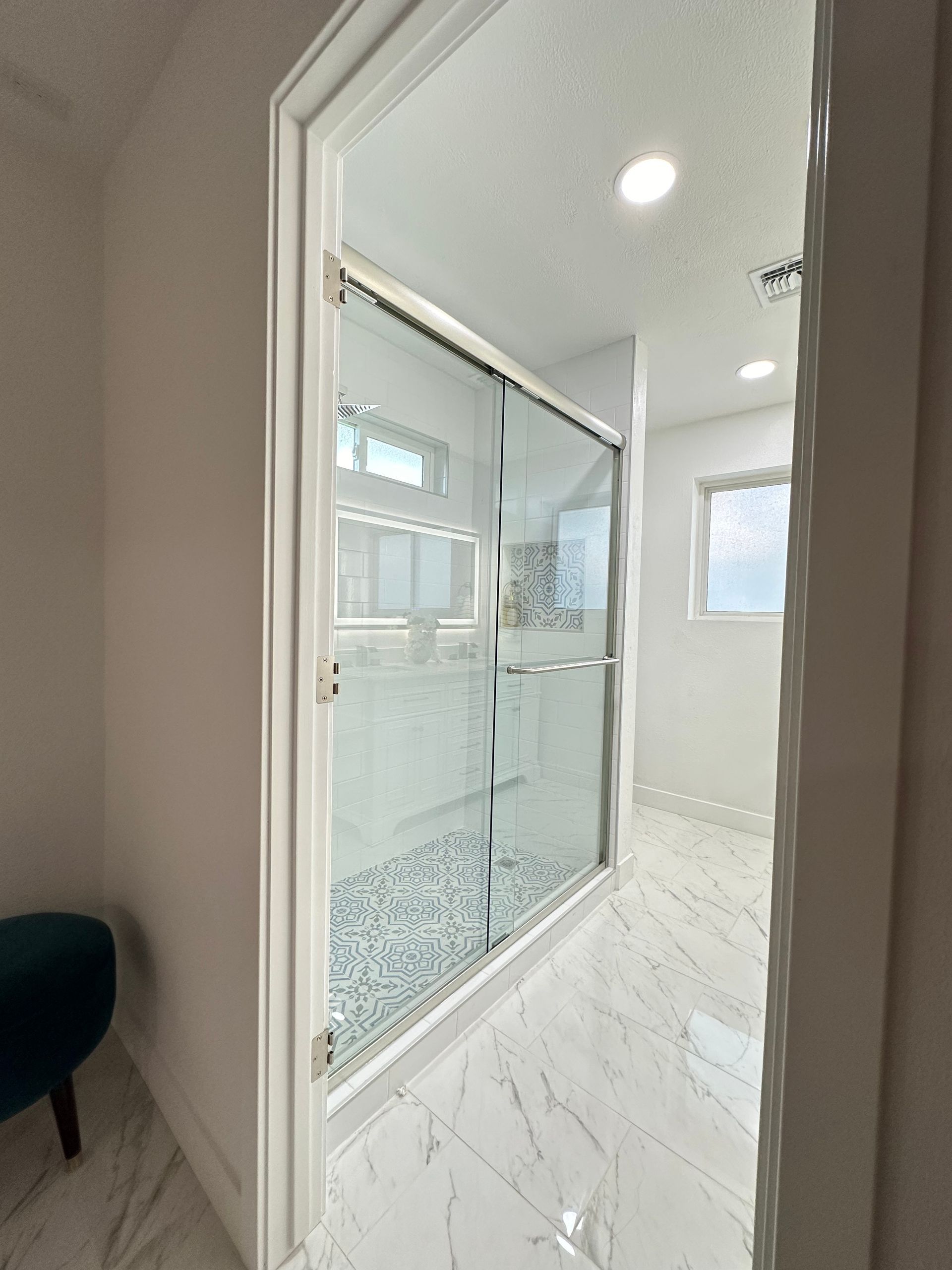 A bathroom with a walk in shower and a window.