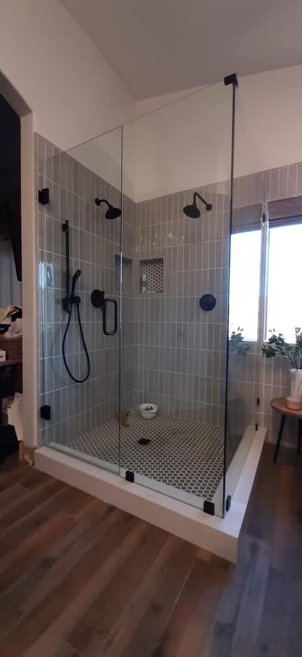 A bathroom with a walk in shower with a glass door.