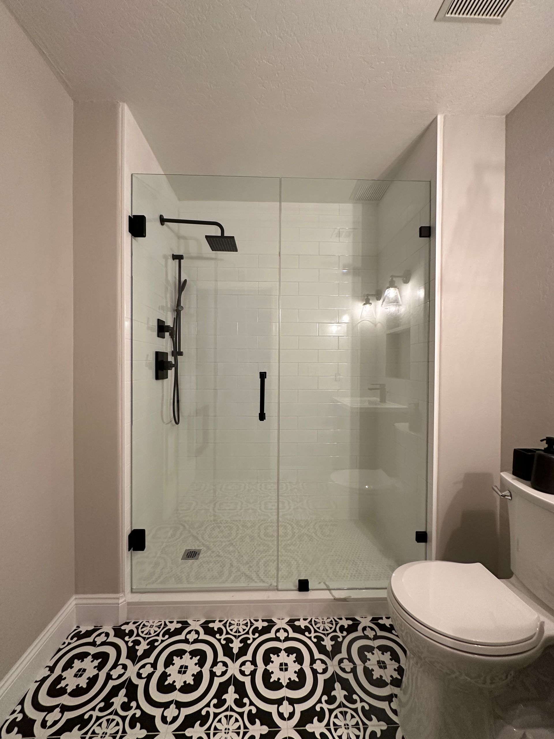 A bathroom with a toilet and a shower with a glass door.