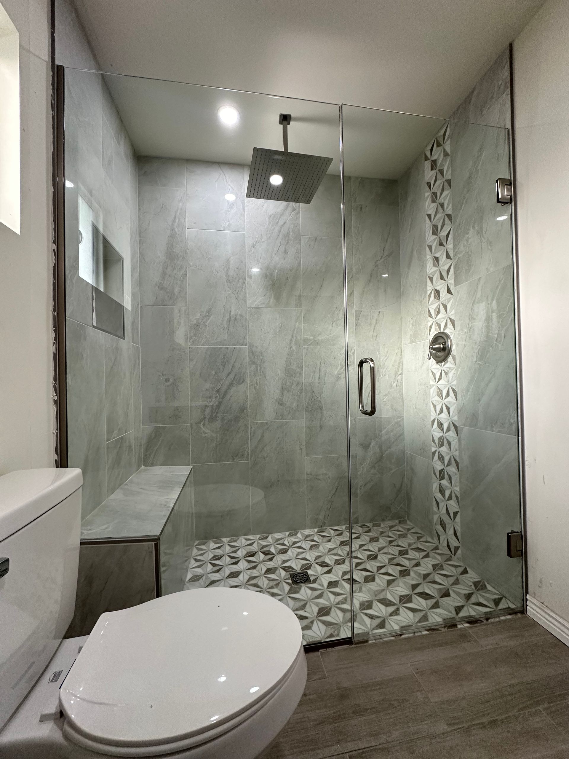 A bathroom with a toilet and a walk in shower with a glass door.