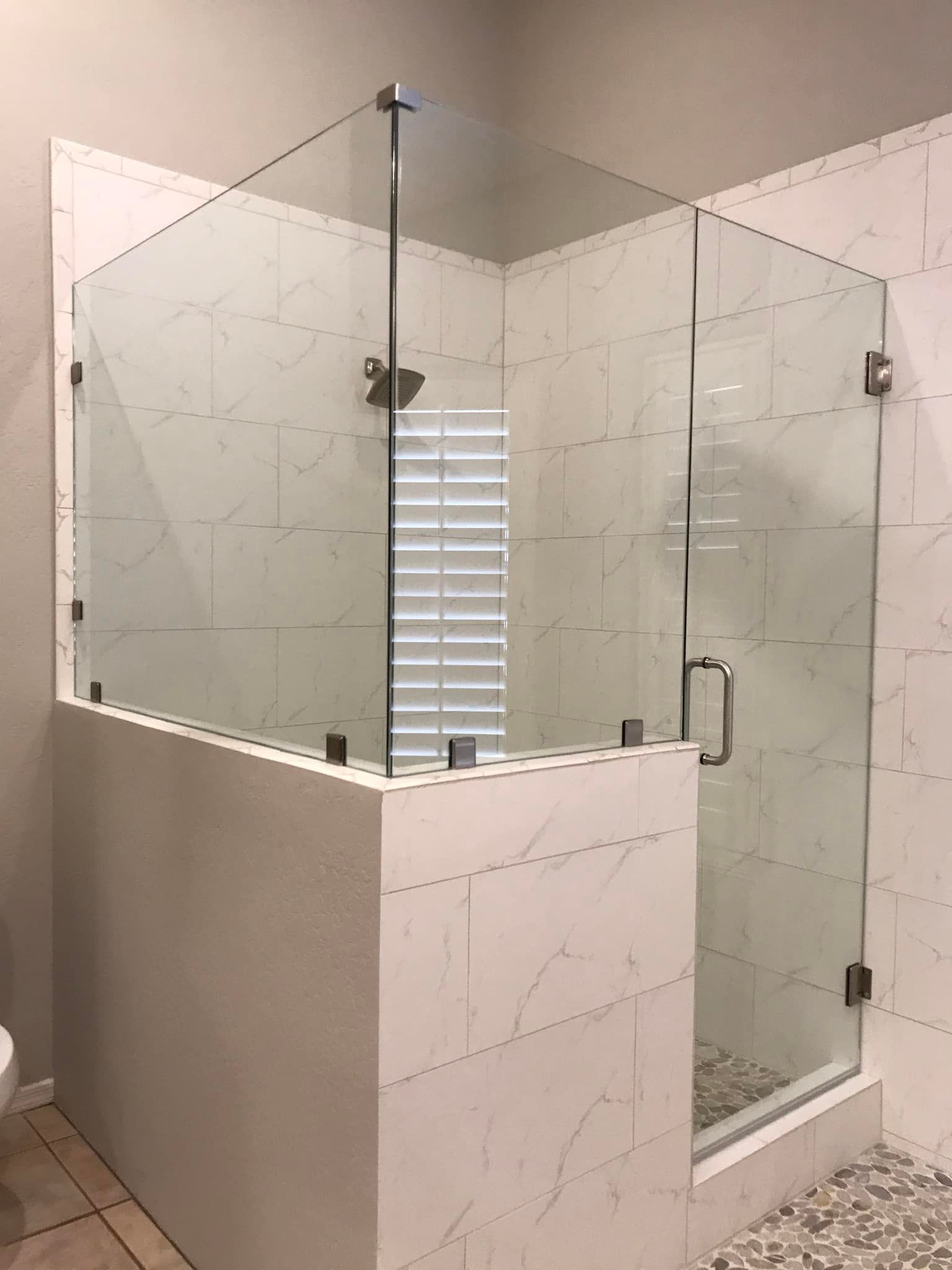 A bathroom with a glass shower door and a toilet.