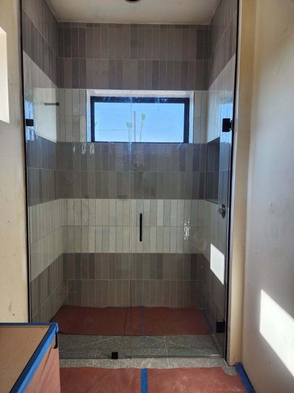A bathroom with a walk in shower and a window.
