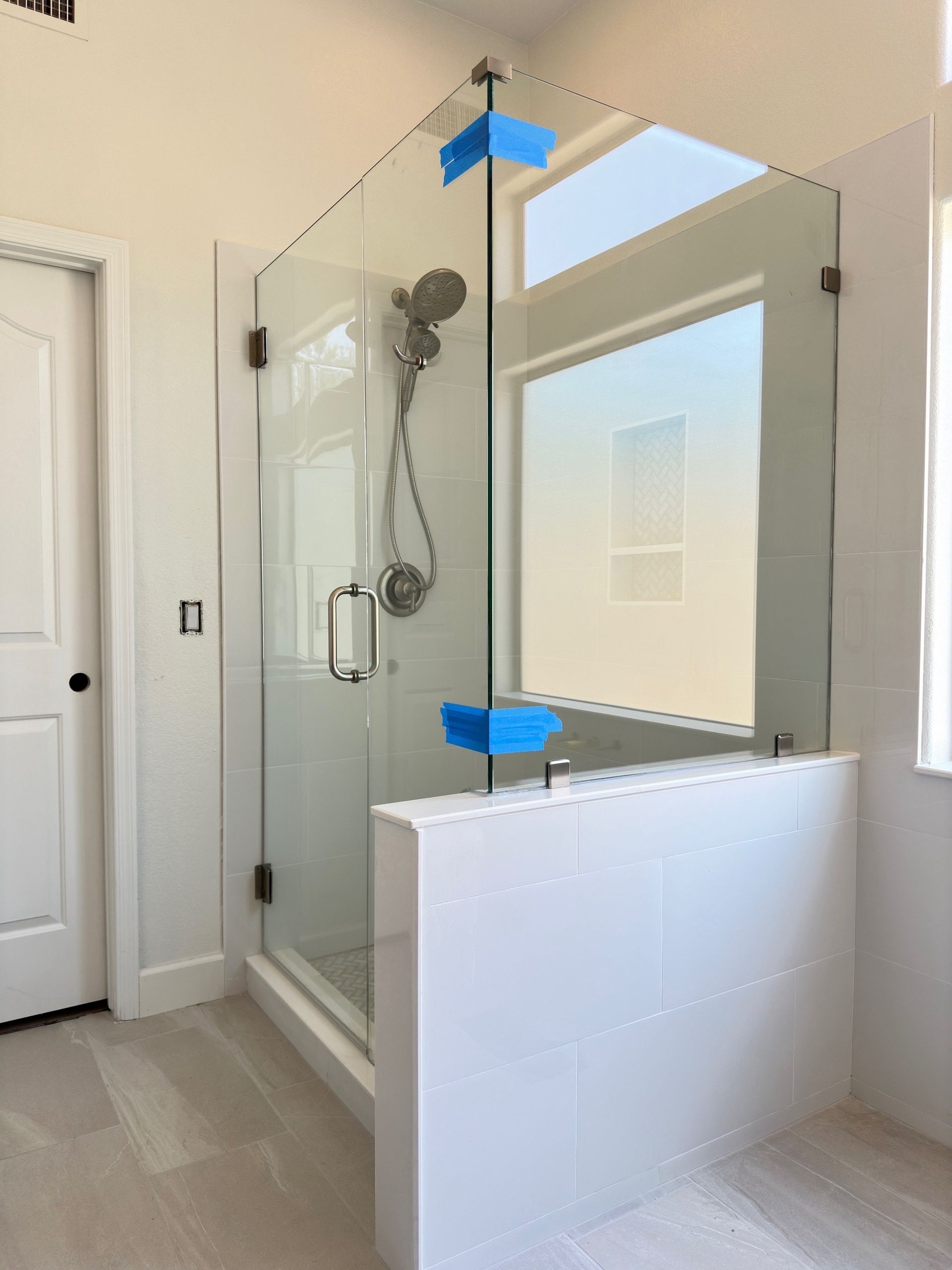 A bathroom with a glass shower door and a window.