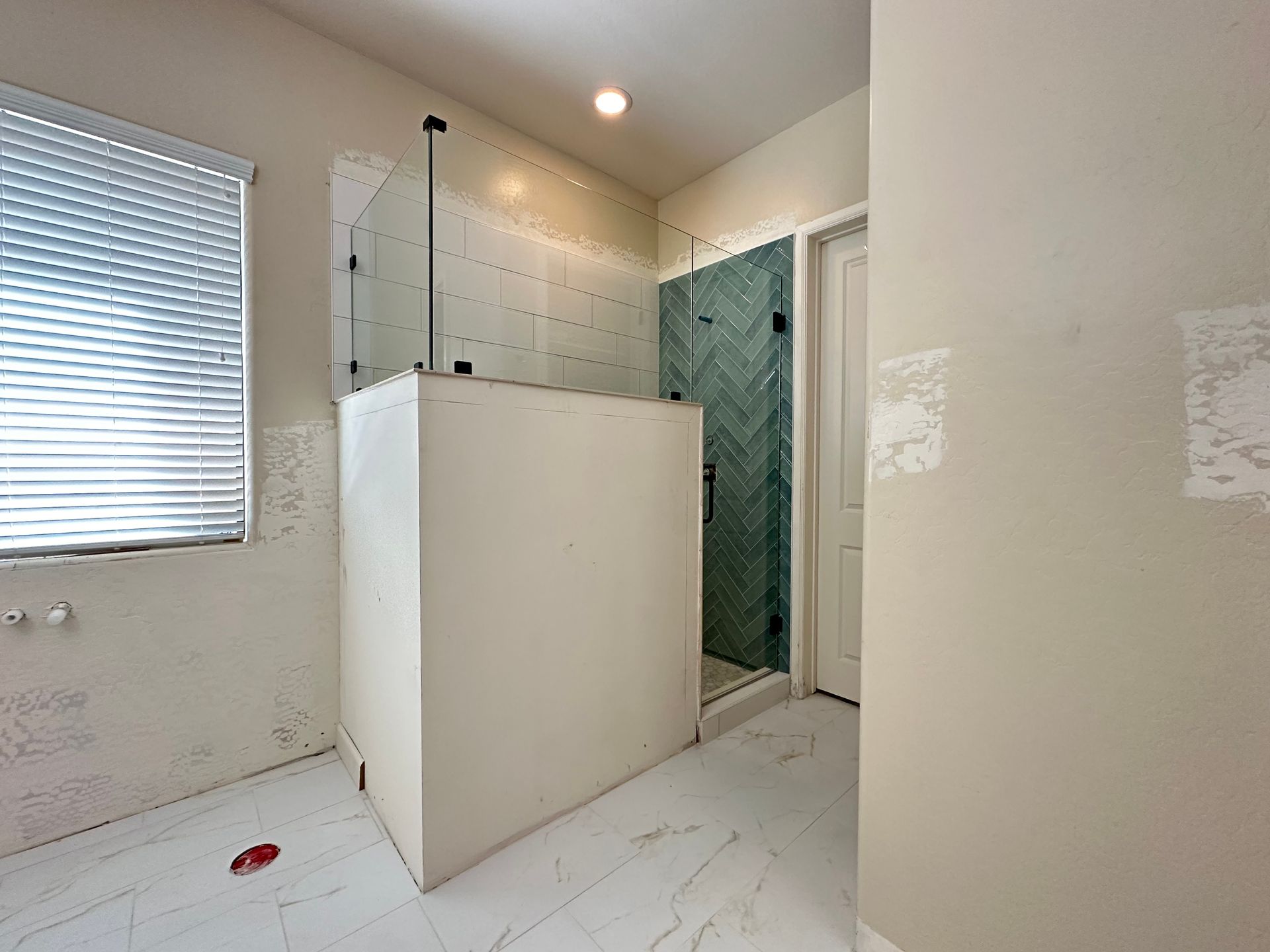 A bathroom with a walk in shower and a window.