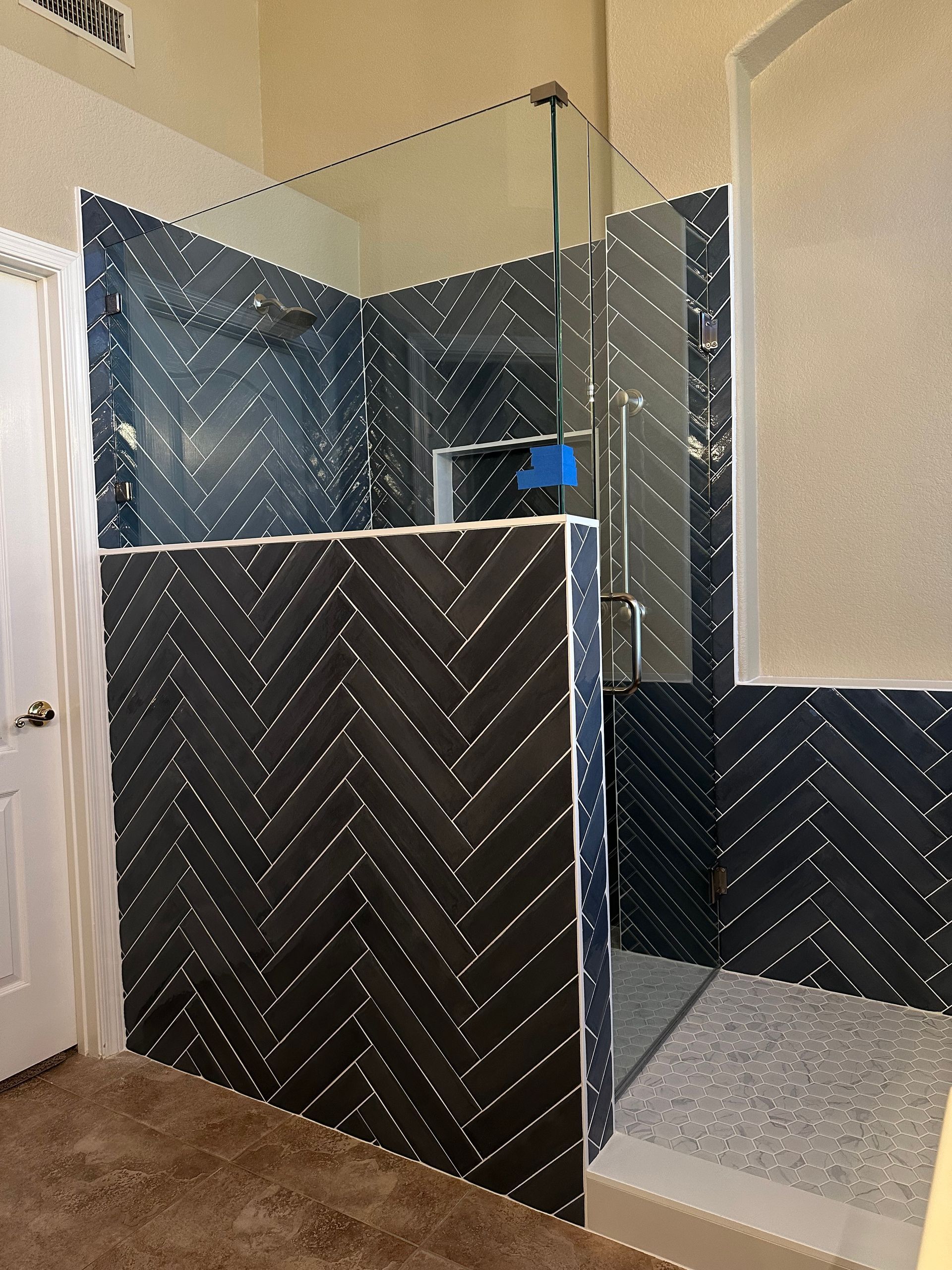 A bathroom with black tiles and a walk in shower.