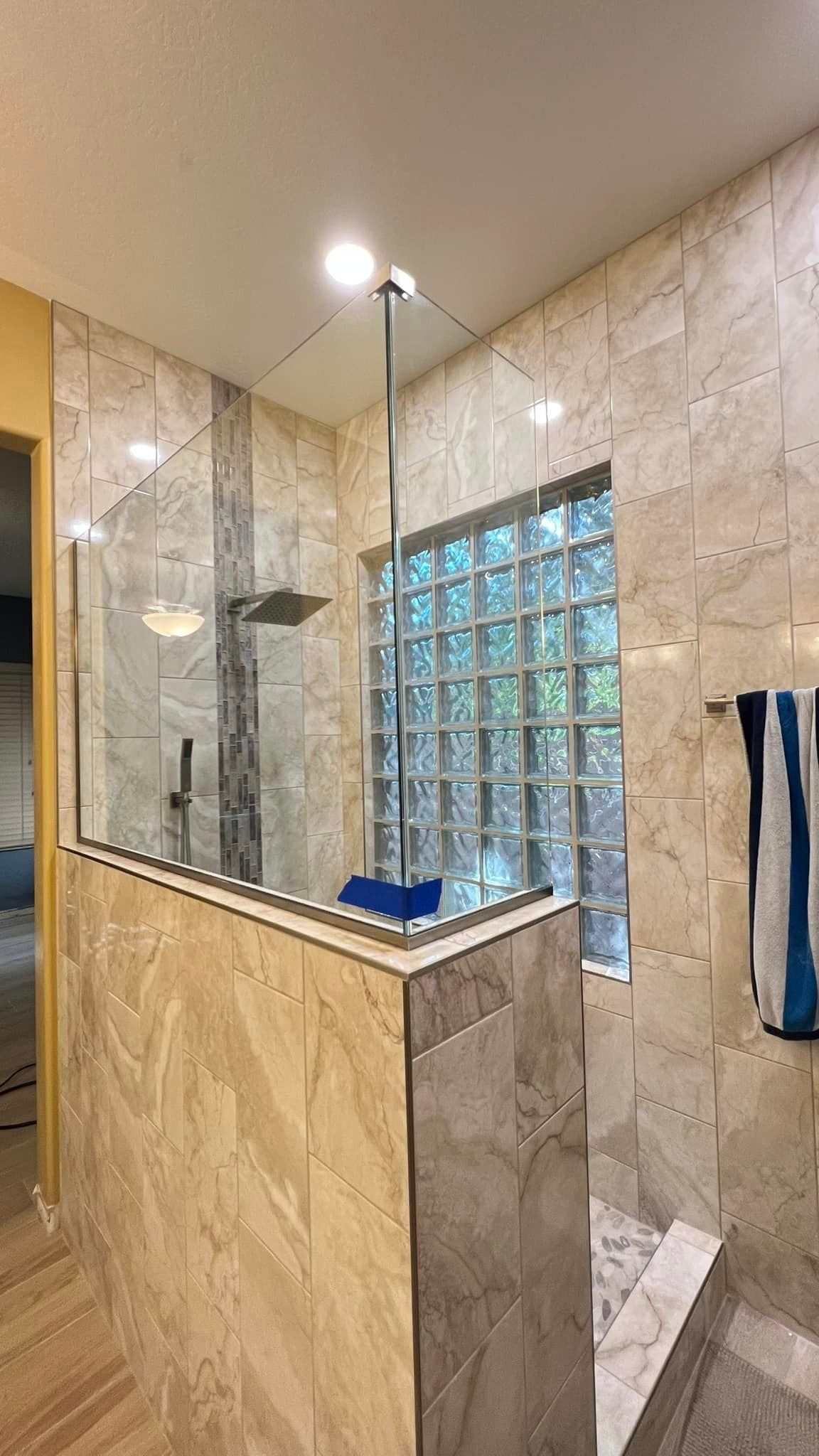 A bathroom with a walk in shower and a window.