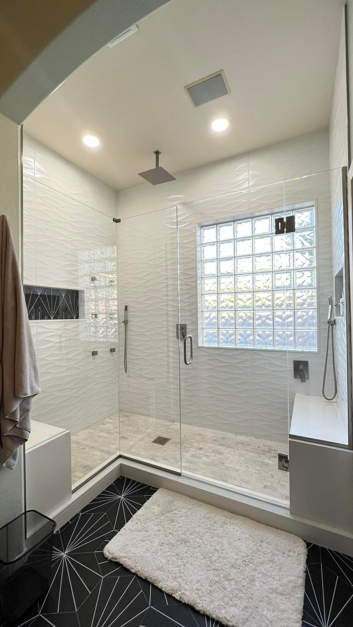 A bathroom with a walk in shower and a window.