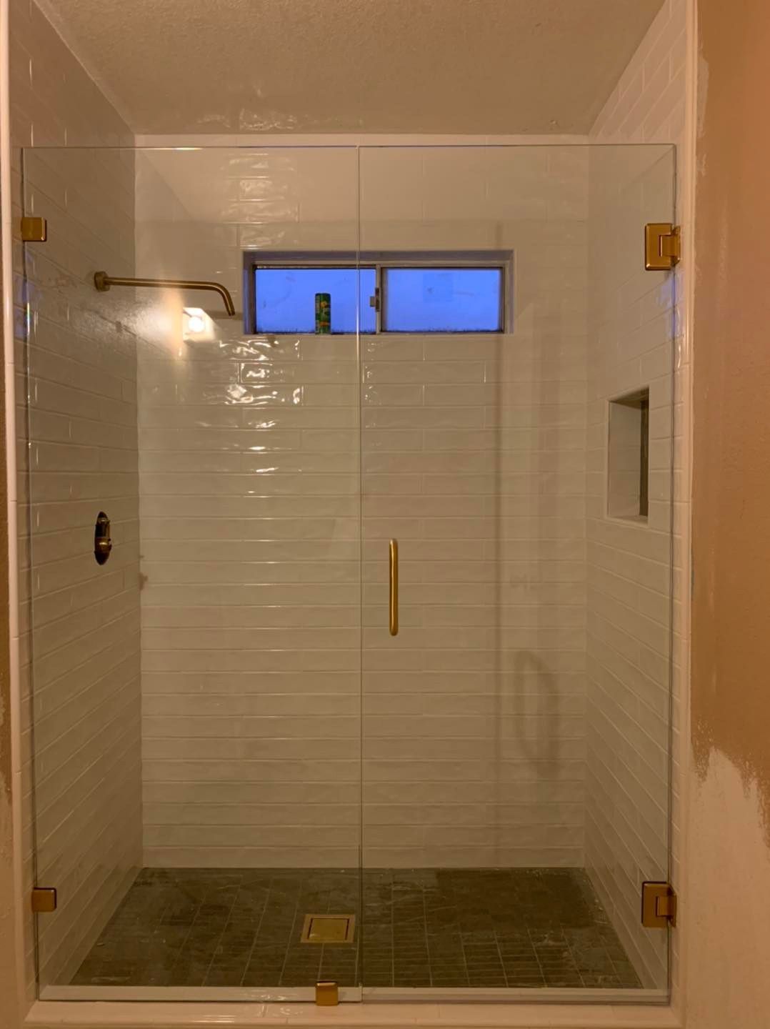 A bathroom with a glass shower door and a window.