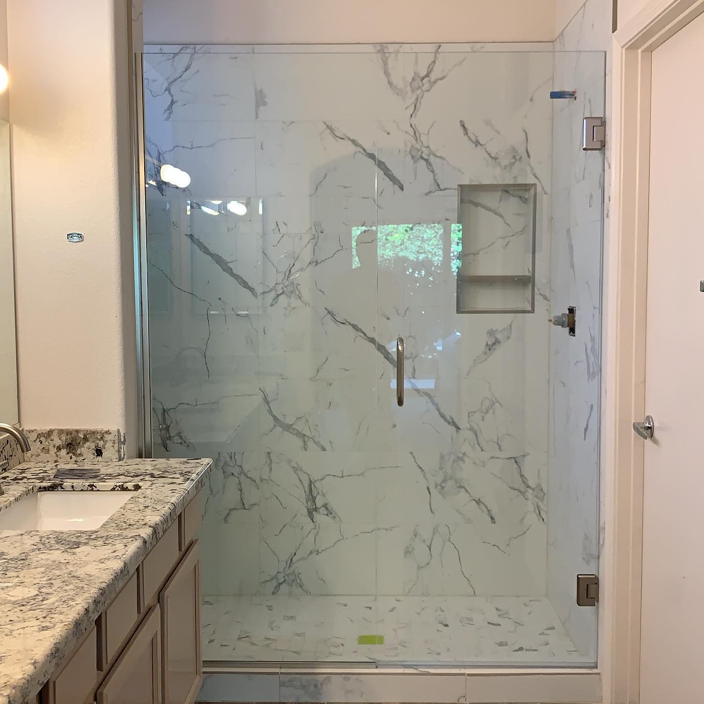 A bathroom with a walk in shower and a sink