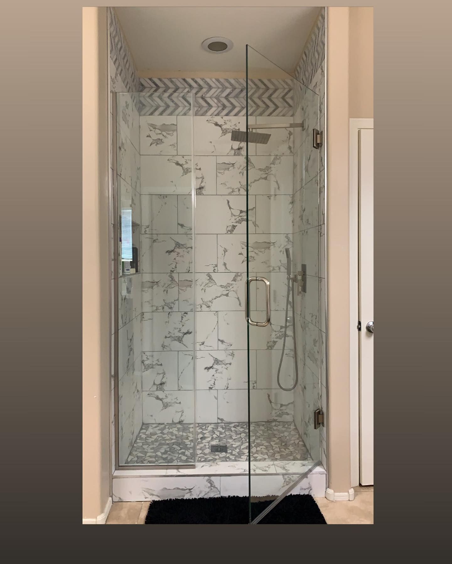 A bathroom with a walk in shower with a glass door