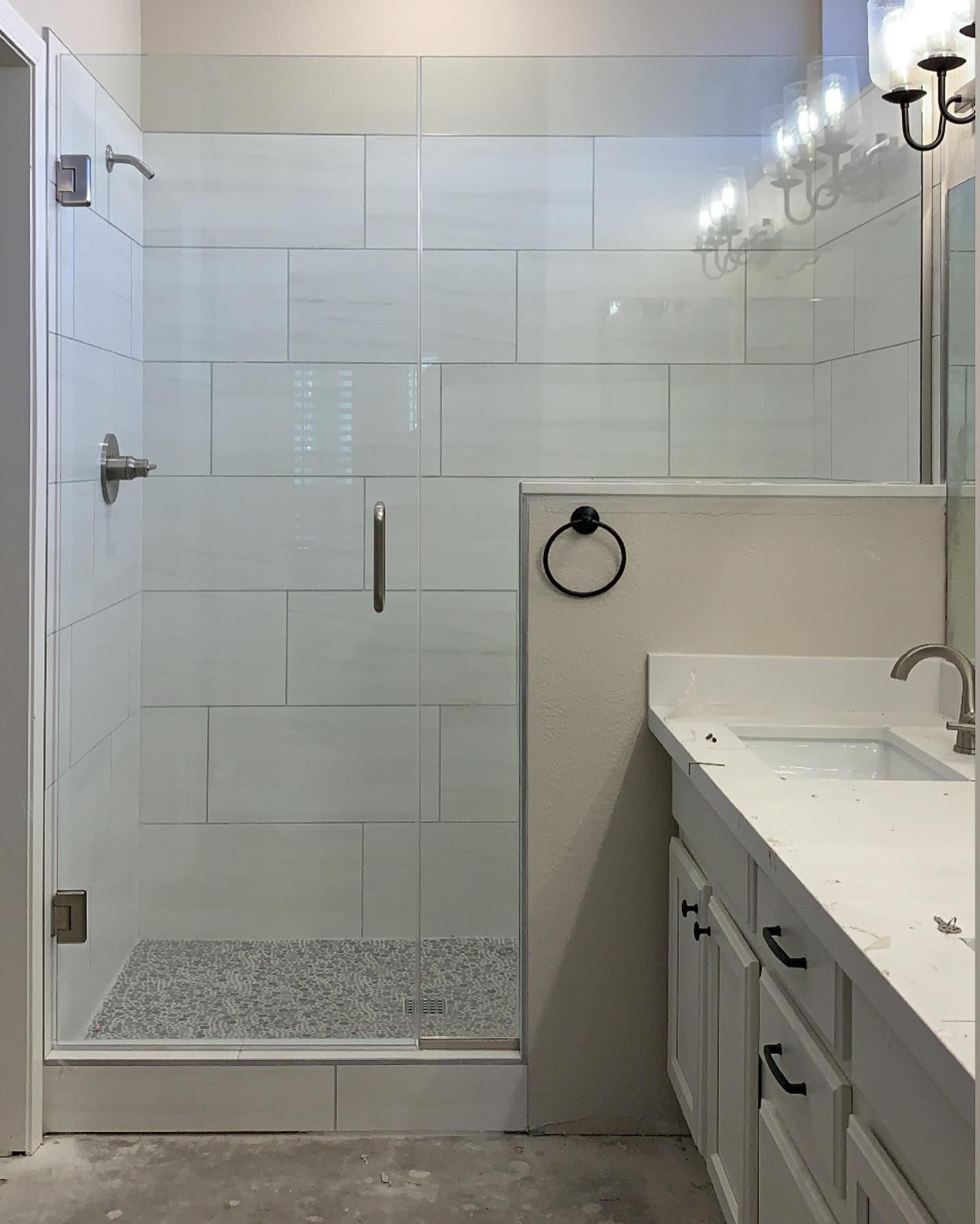 A bathroom with a walk in shower, sink and mirror.