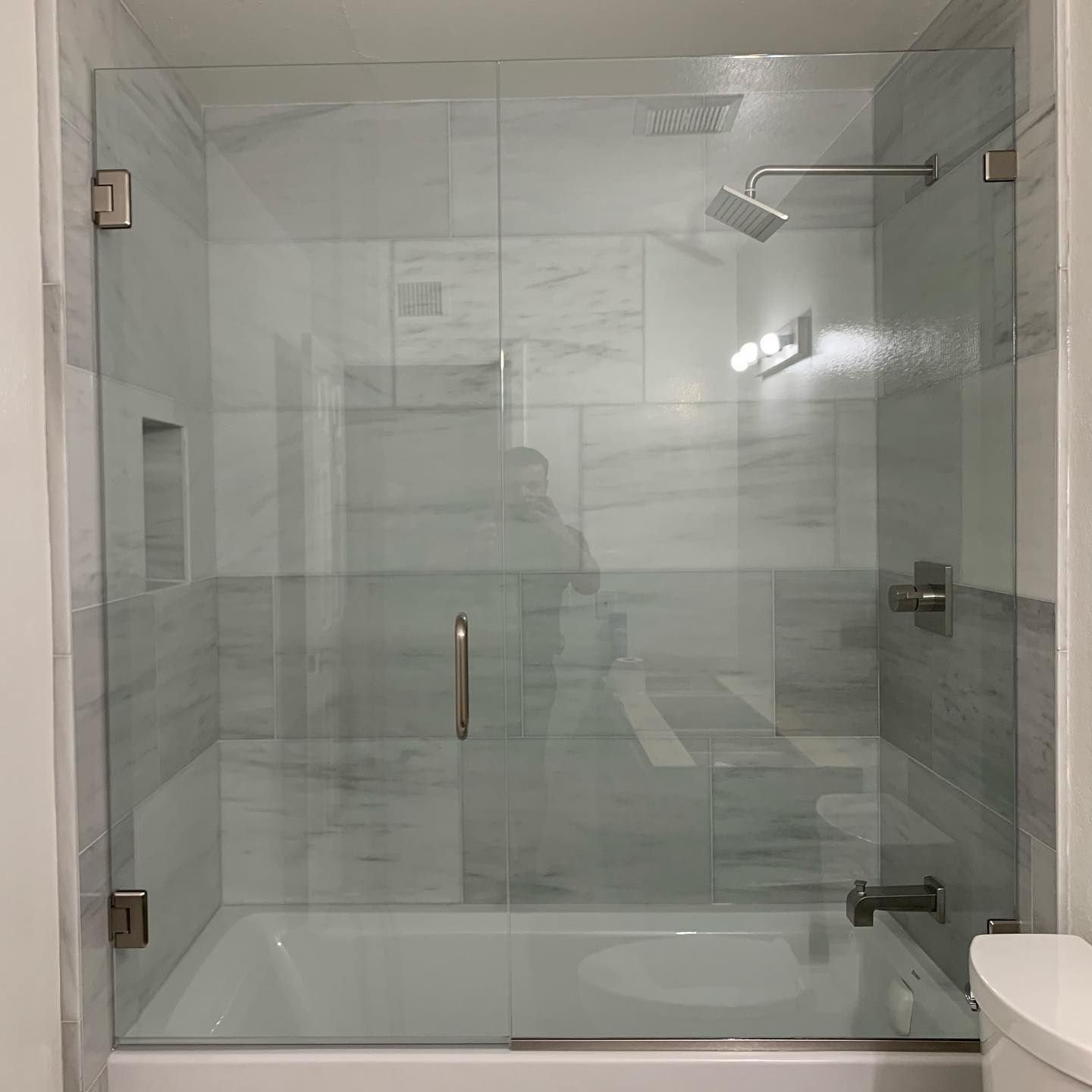 A bathroom with a bathtub and a shower with a glass door.