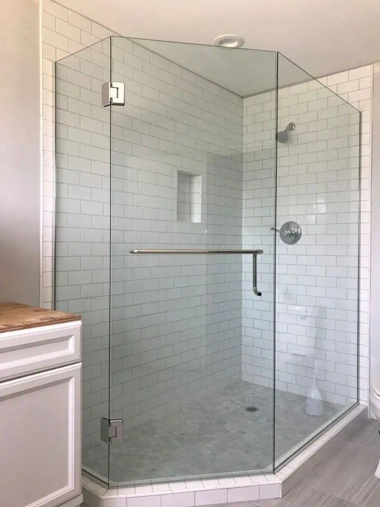 A bathroom with a walk in shower with a glass door.