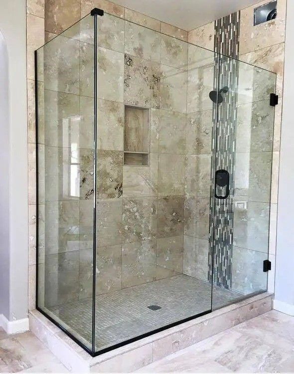 A bathroom with a walk in shower with a glass door.