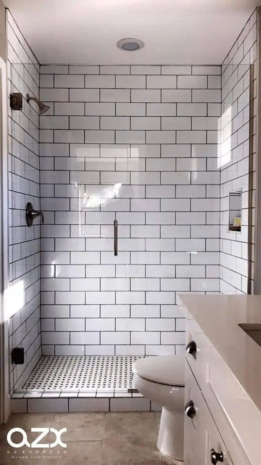 A bathroom with white subway tiles and a walk in shower.