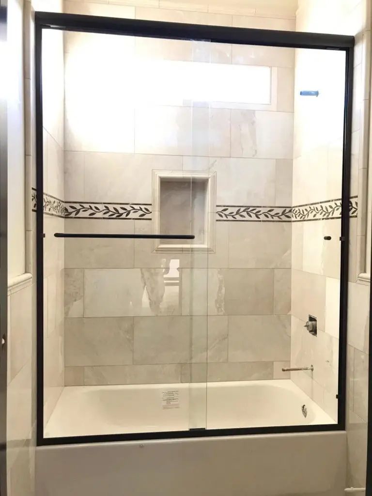 A bathroom with a bathtub and a sliding glass shower door.