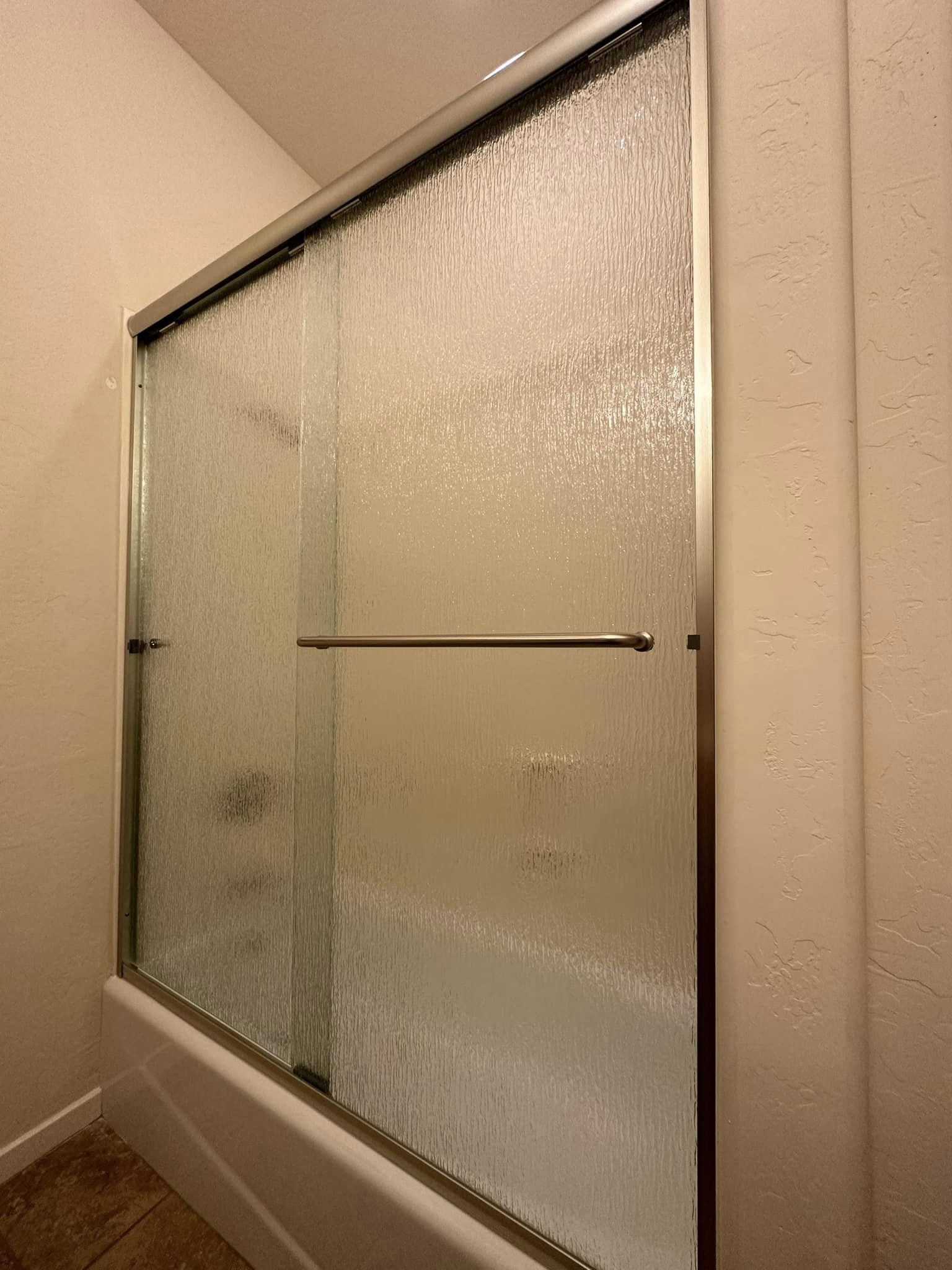 A bathroom with a sliding glass shower door and a bathtub.