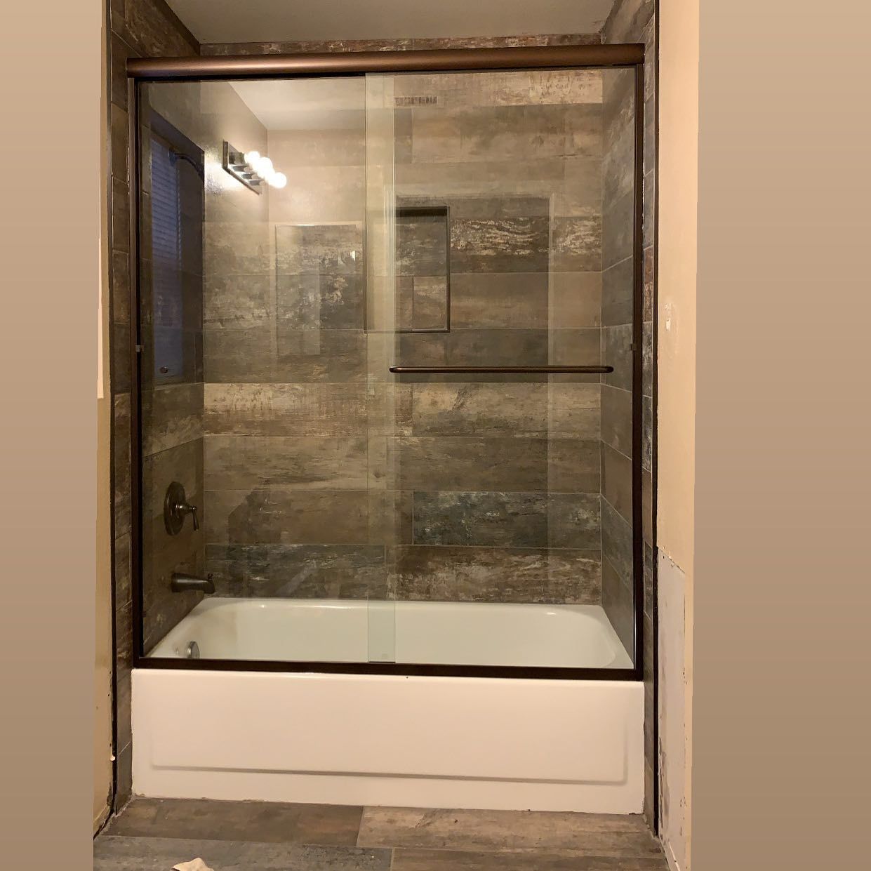A bathroom with a bathtub and a glass shower door.