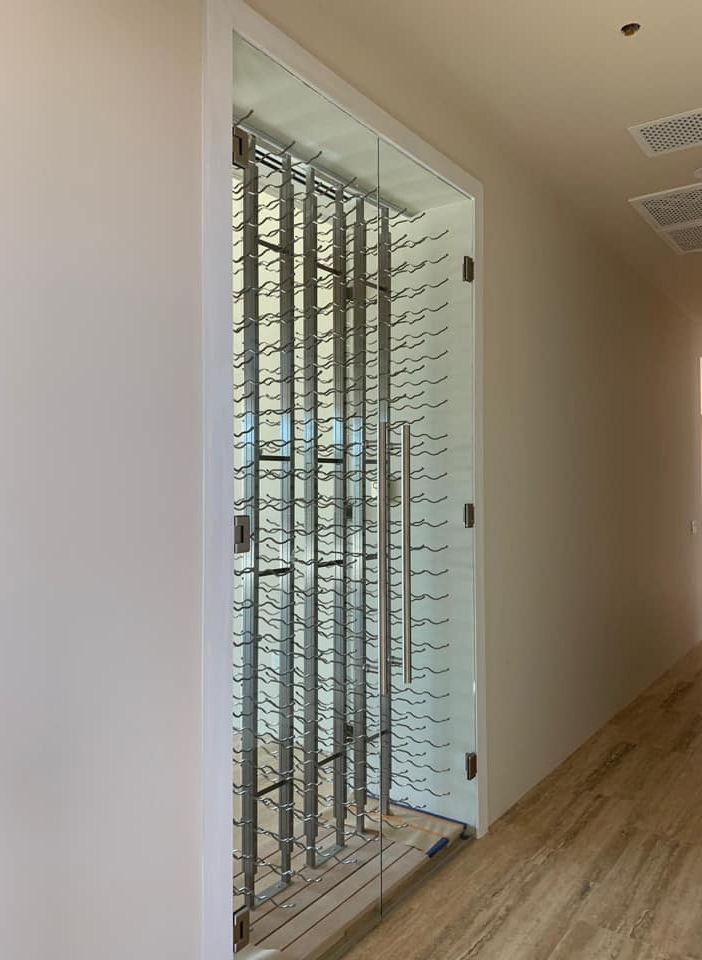 A hallway with a glass door and a wine rack.