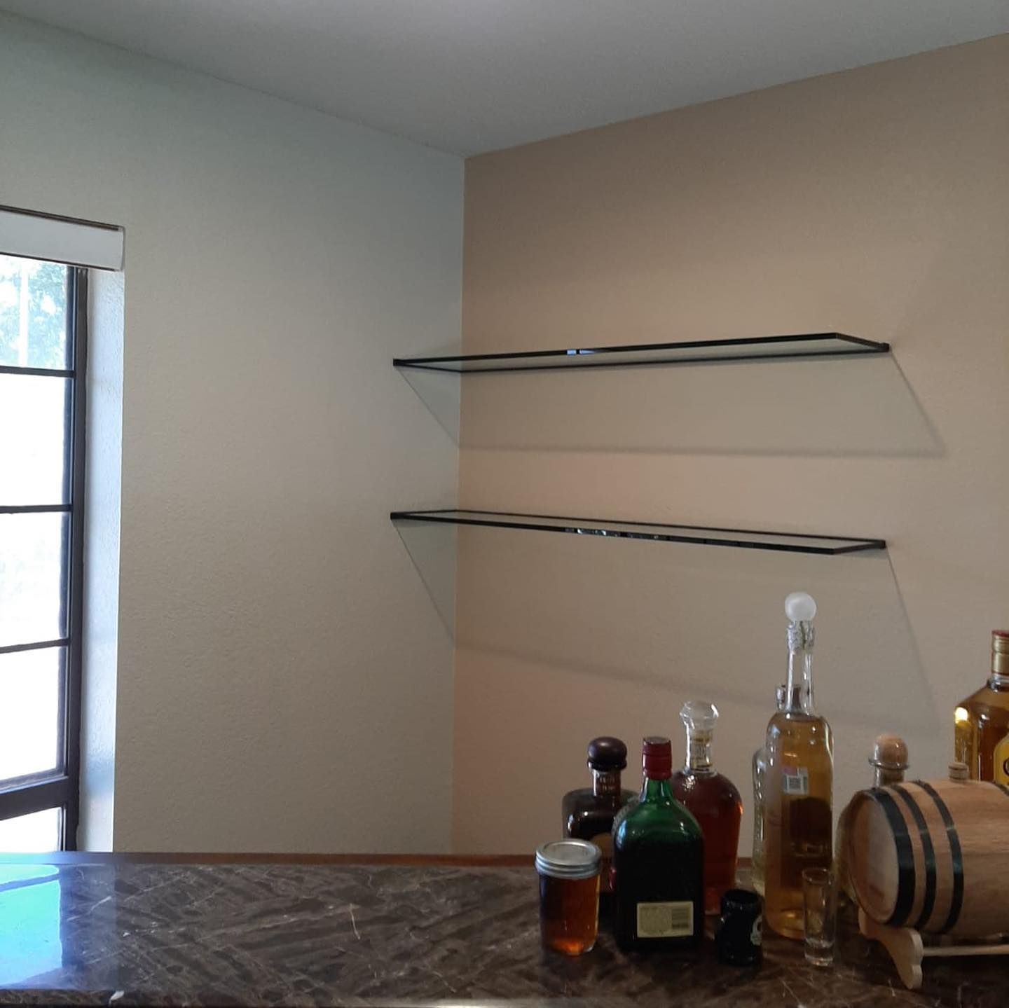 Several bottles of alcohol are on a counter in front of a window