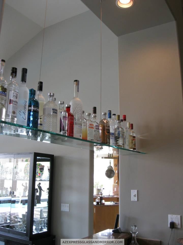 Bottles of alcohol are lined up on a glass shelf