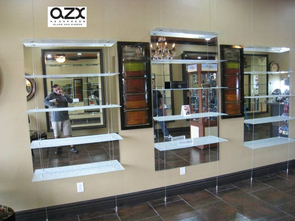 A man is taking a picture of himself in a room with shelves and mirrors