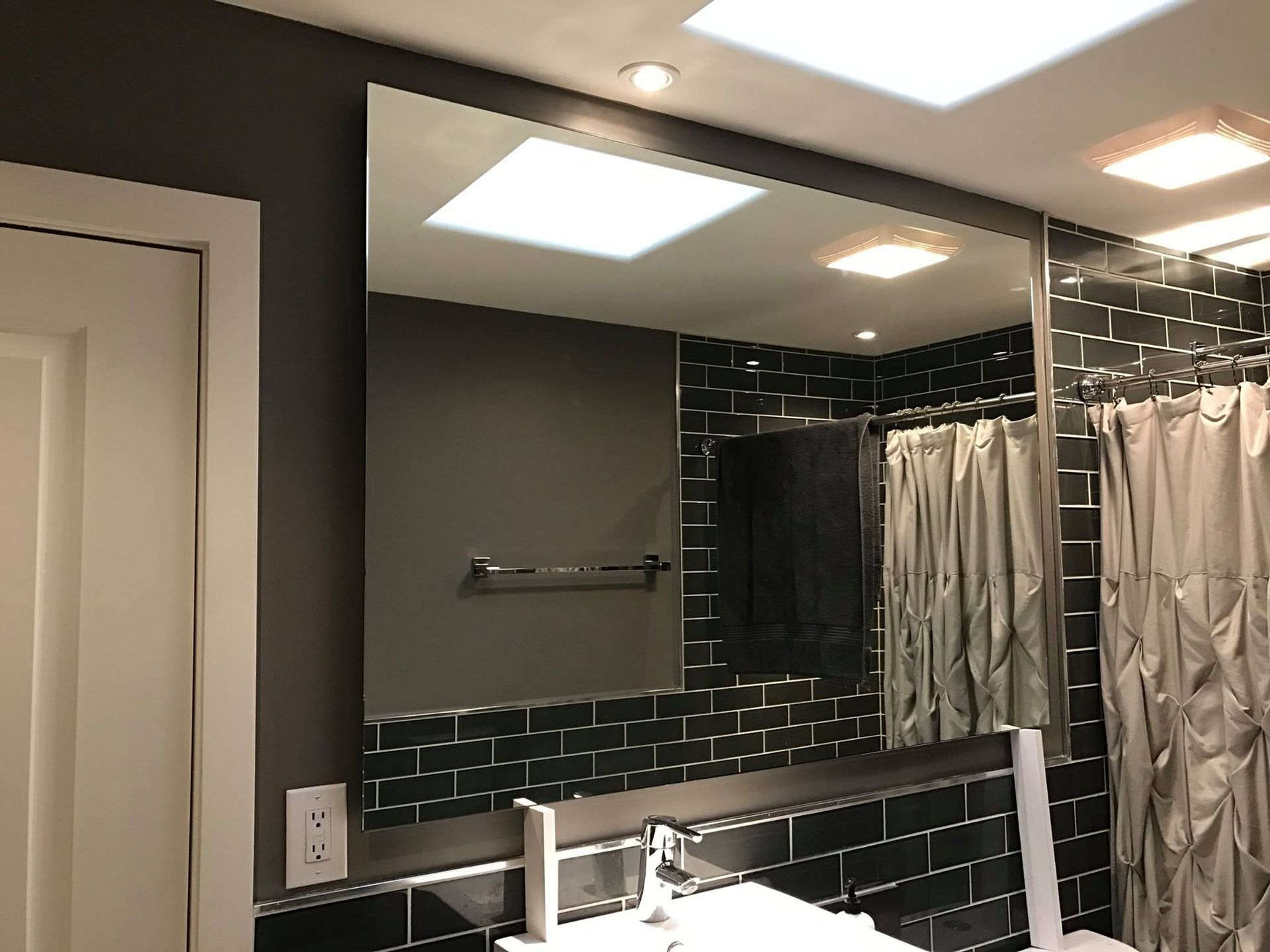 A bathroom with black tiles and a large mirror