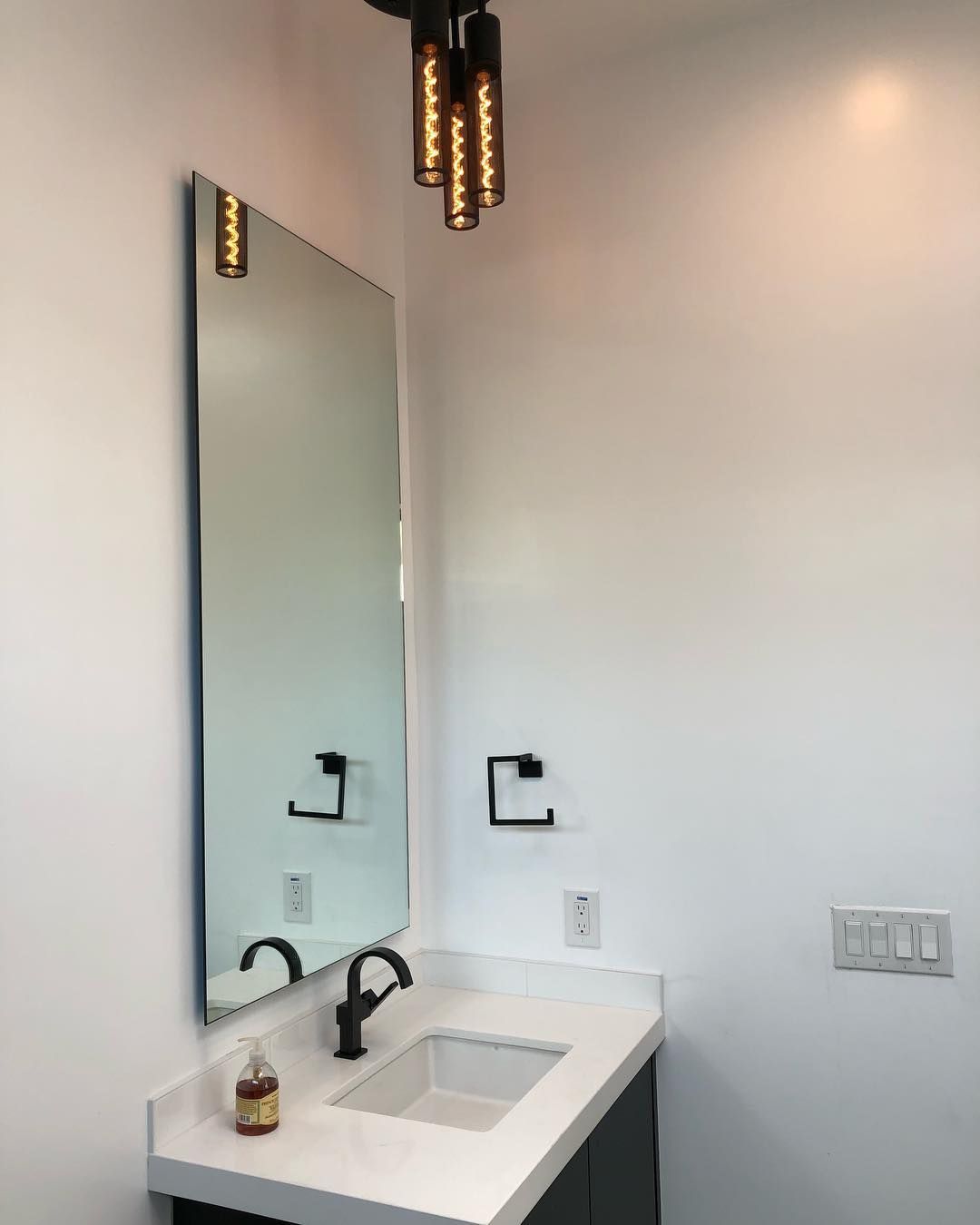 A bathroom with a sink, mirror and light fixtures.