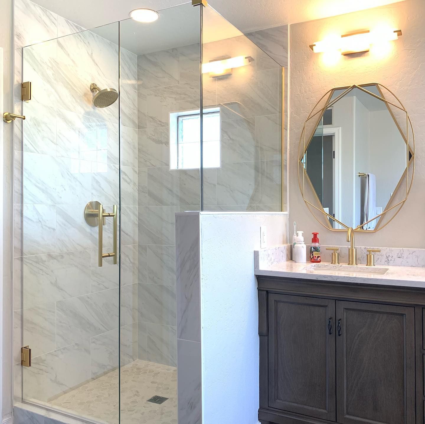A bathroom with a walk in shower, sink, mirror and vanity.