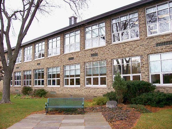 A large brick building with lots of windows and a bench in front of it