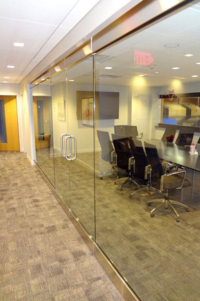 A conference room with a glass wall and a red exit sign