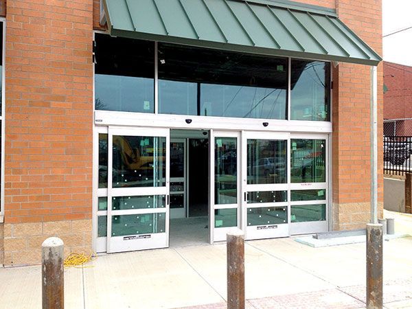 A brick building with sliding glass doors and a green awning