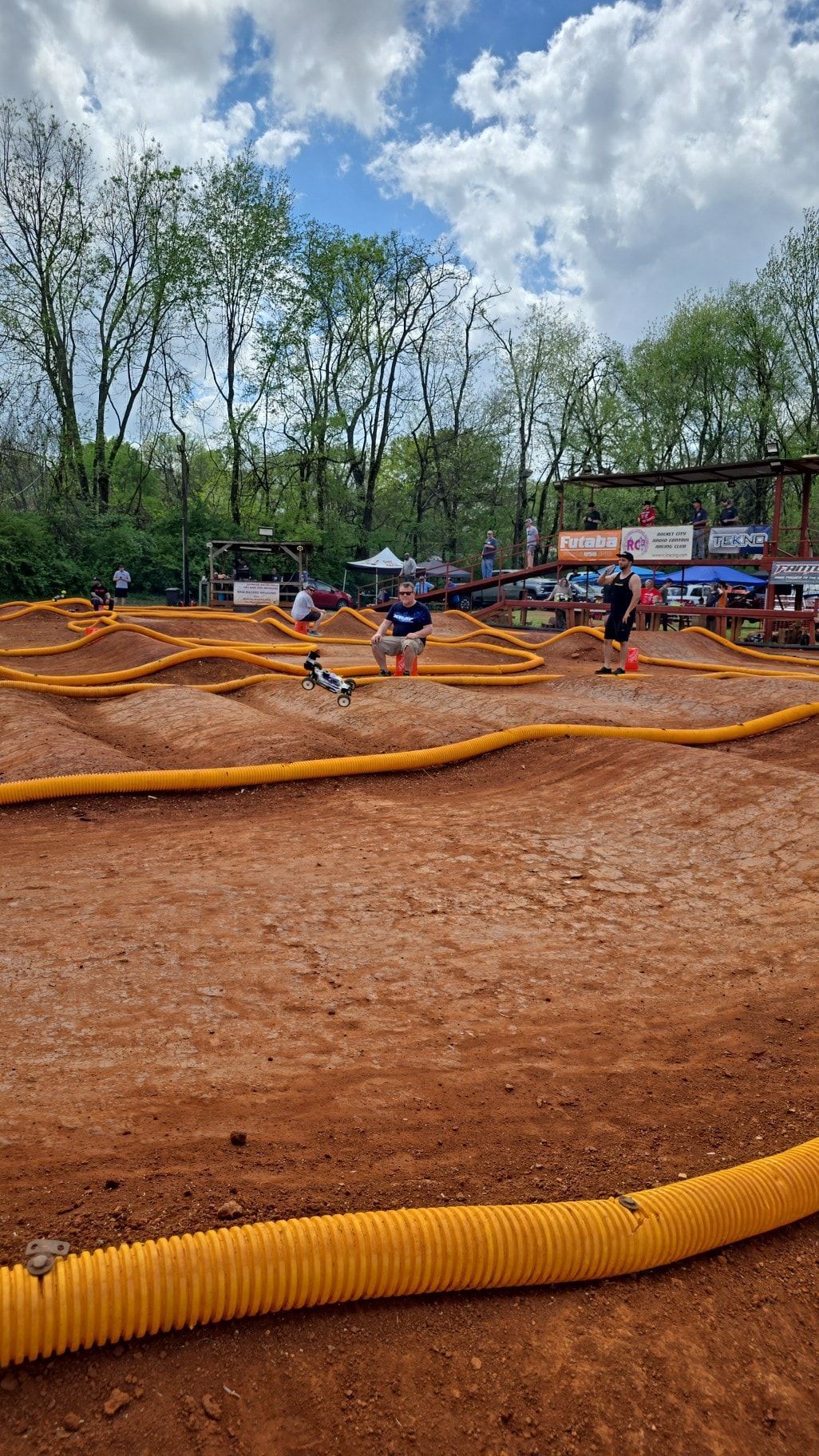 A person is riding a remote control car on a dirt track.