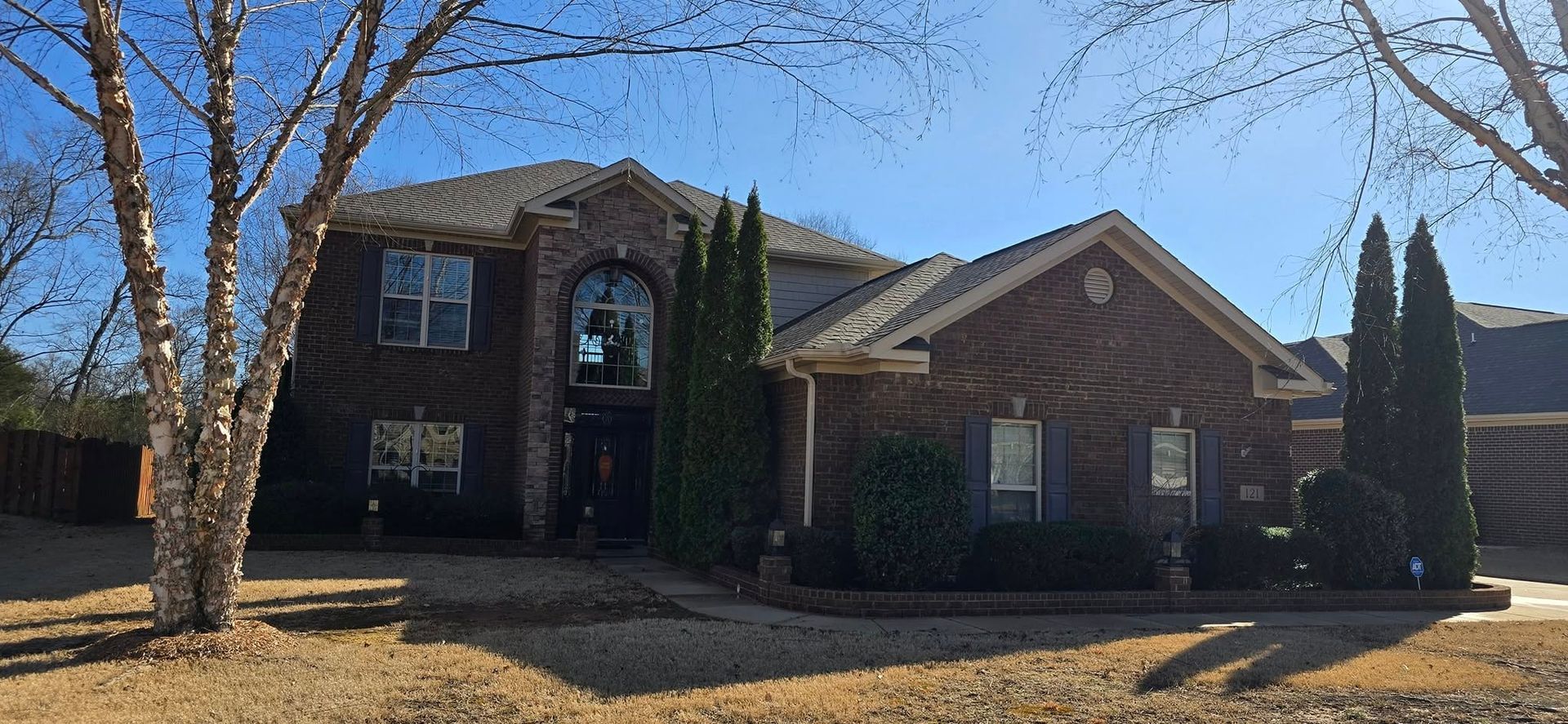 A large brick house with trees in front of it on a sunny day.