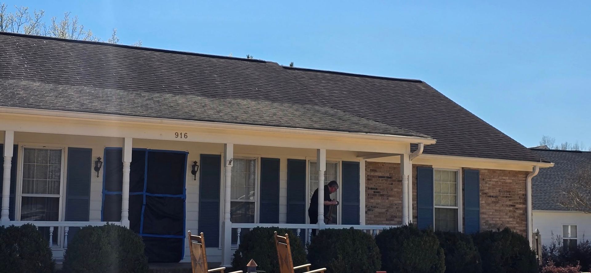 A brick house with a screened in porch and blue shutters
