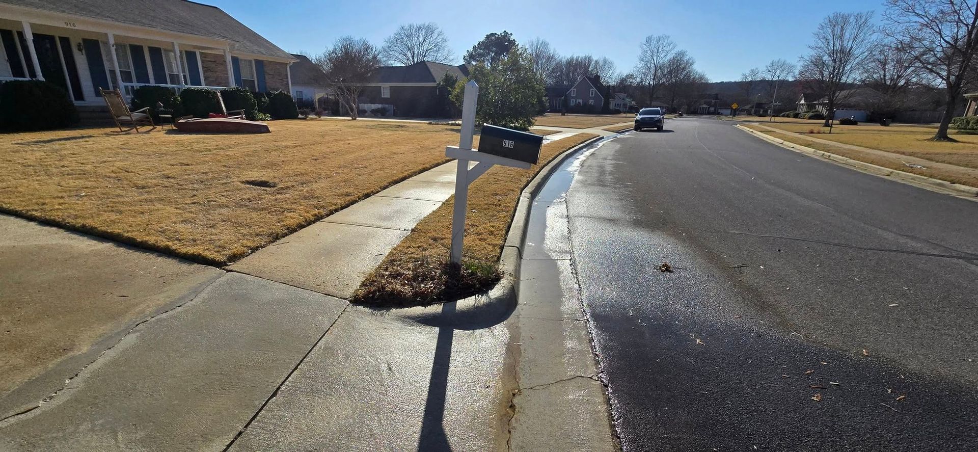A white mailbox is sitting on the curb of a residential street.