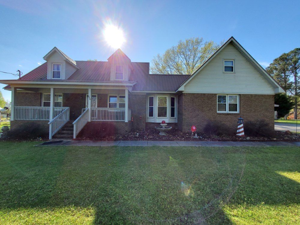 A large brick house with a porch and stairs is for sale.