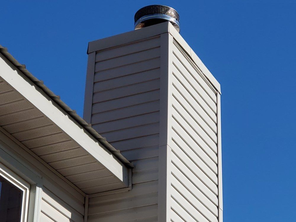 A chimney on the side of a house with a blue sky in the background