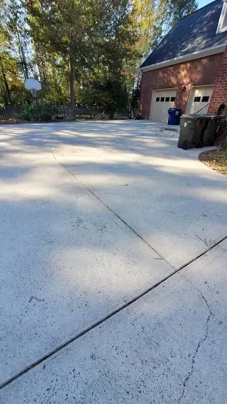 A concrete driveway with a brick house in the background.