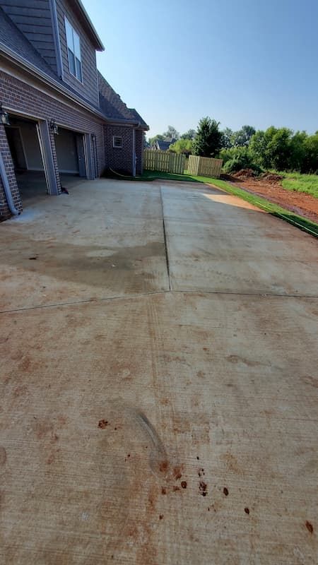 A concrete driveway with a brick house in the background.