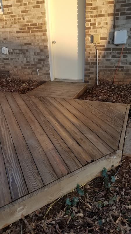 A wooden deck is sitting in front of a brick building.