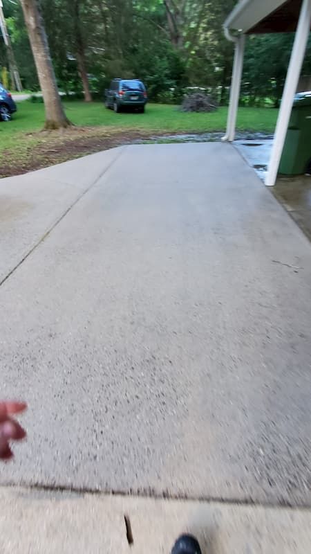 A concrete driveway with a car parked in the background.