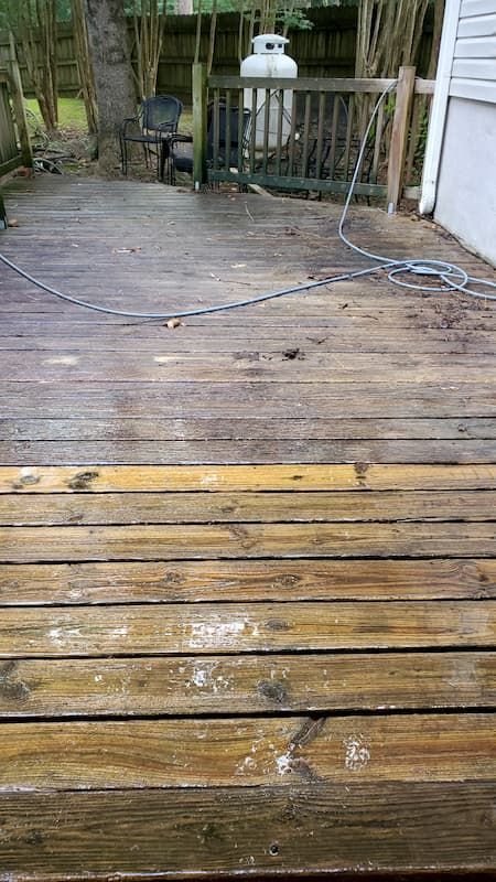 A wooden deck is being cleaned with a pressure washer.
