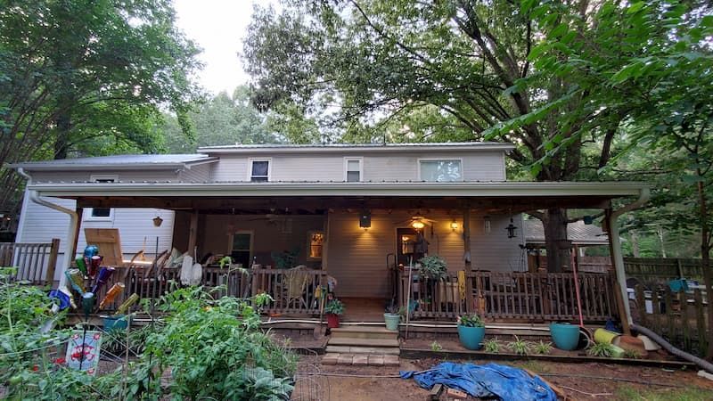 The front of a house with a porch and trees in the background.