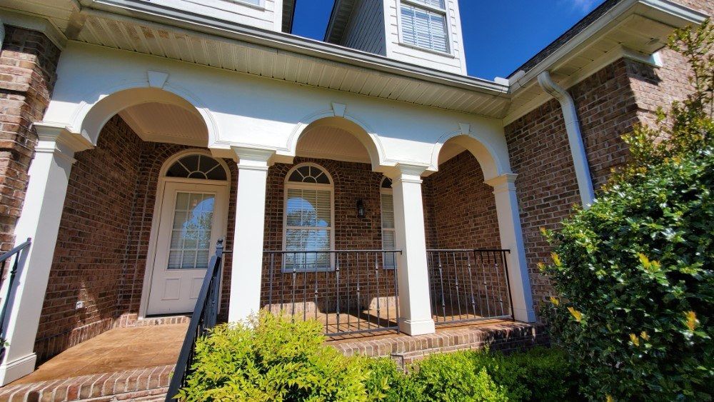 A large brick house with a white porch and arched windows.